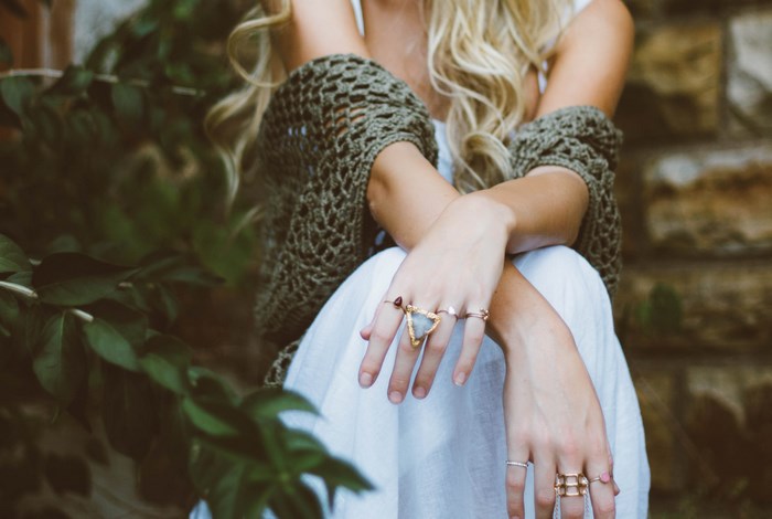 Woman wearing rings and a white dress with foliage