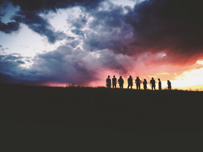 Group of people silhouetted against a colorful sunset sky