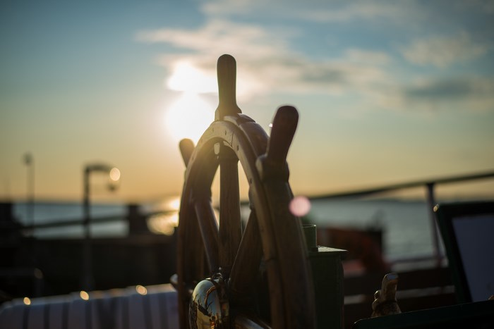 Ship's steering wheel at sunset