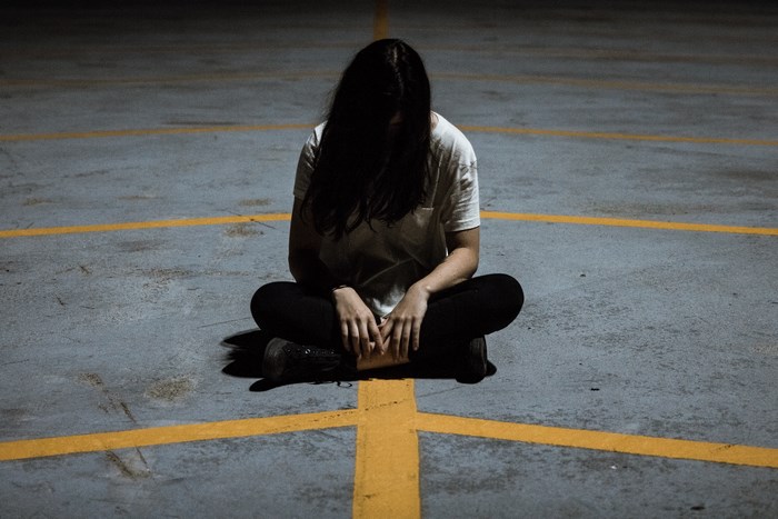 Woman sitting alone in a parking lot