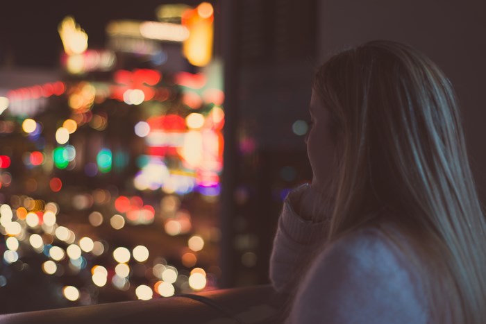 Woman looking at bokeh city lights at night