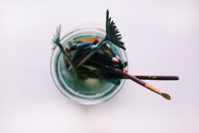 Top-down view of art supplies in a glass jar
