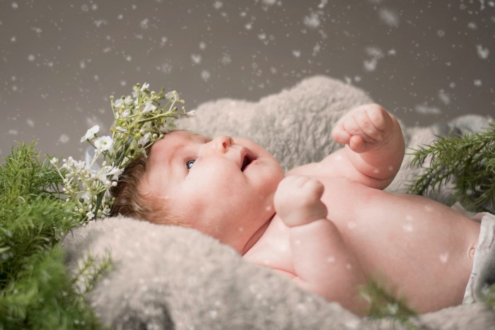 Baby wearing a flower crown with pine branches and snow