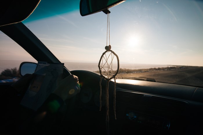 Driver holding map in car with dreamcatcher