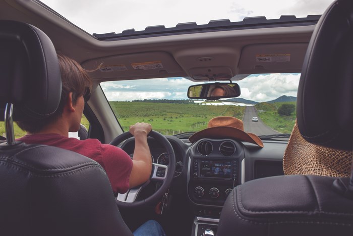 Man driving car on road trip with passenger