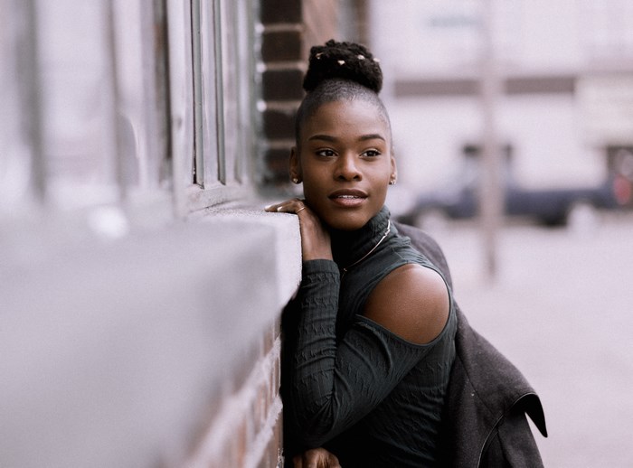 Woman leaning on a brick wall