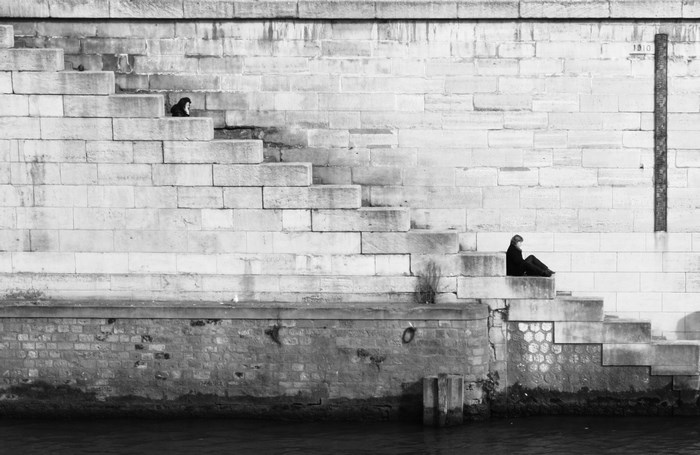 Two people sitting on stone steps by a river