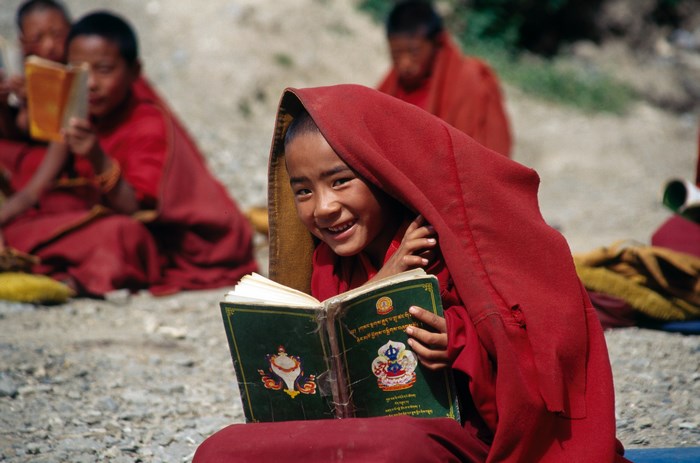 Smiling Tibetan Child Reading a Book Outdoors