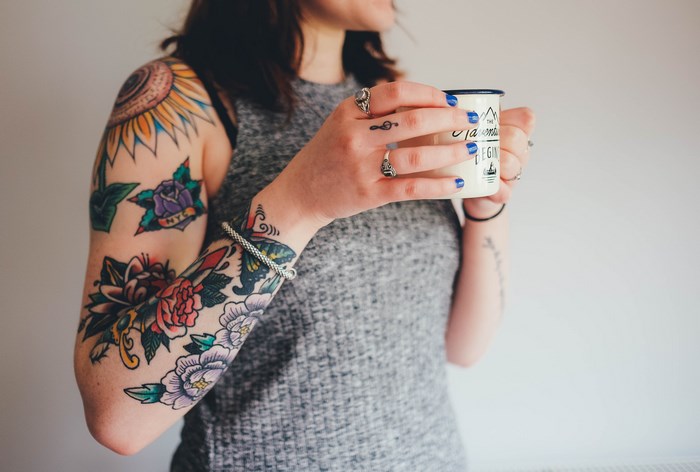Woman with tattoos holding a mug