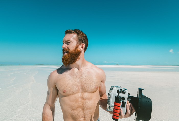 Man with beard holding camera on a beach