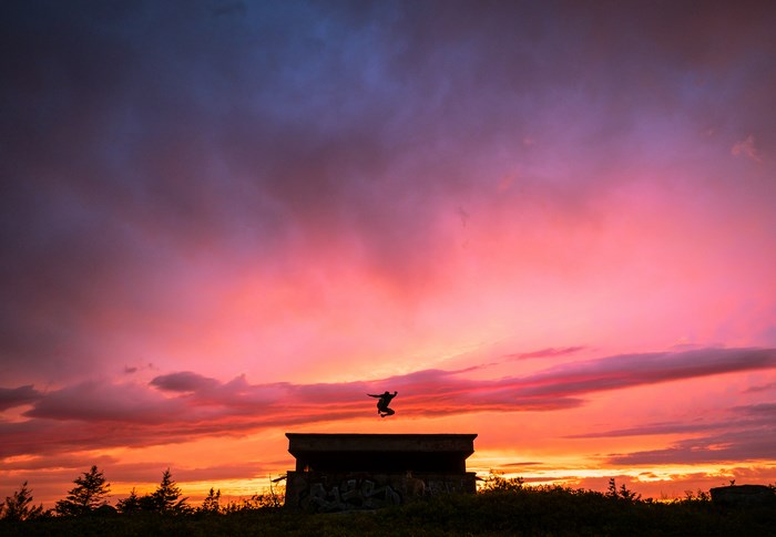 Silhouette of a person jumping over a bunker at sunset
