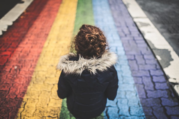 Child walking on a rainbow crosswalk
