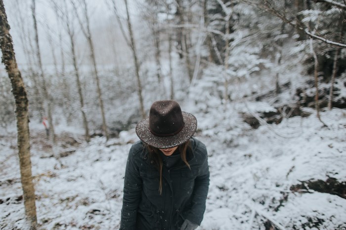 Woman in hat hiking in snowy woodland