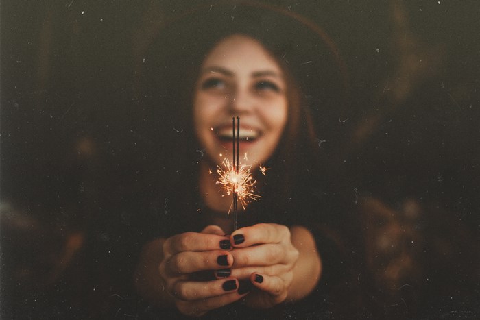 Woman holding a sparkler with a smile