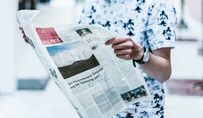 Man Reading Newspaper with Politics and Wind Turbines