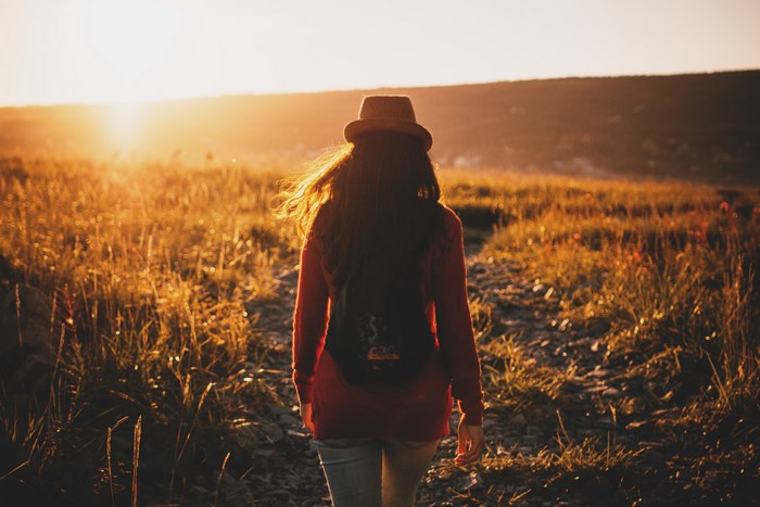 Woman with backpack walking at sunset