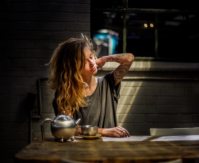 Tattooed Woman Sitting at Table in Sunlight