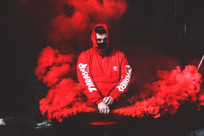 Man in red Thrasher jacket with red smoke bomb