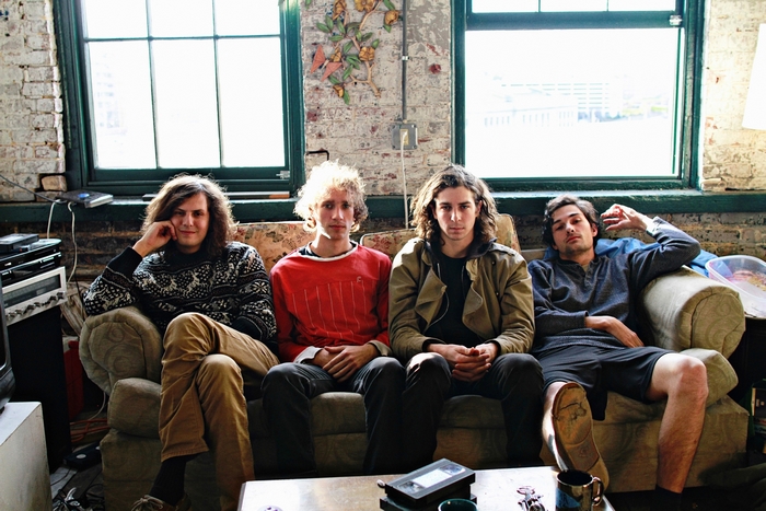 Four young men sitting on a couch in a room