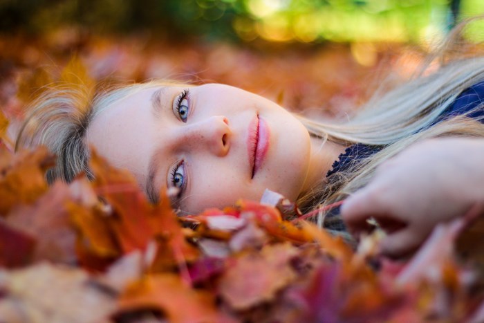Young girl laying in autumn leaves