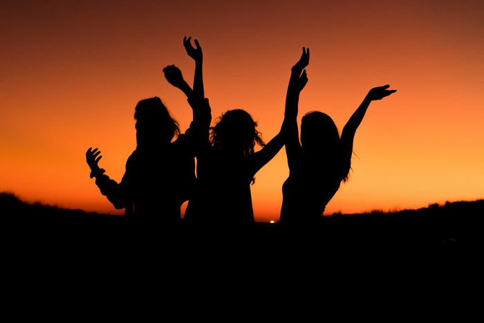 Three friends dancing at sunset