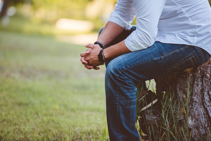 Man in jeans sitting on a tree stump
