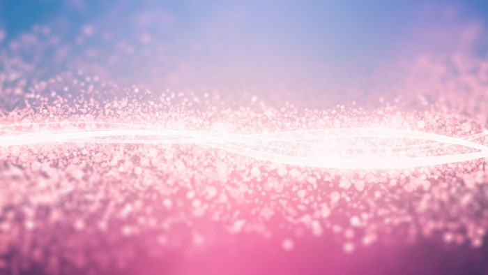 Glitter particles and light streaks on a pink and blue gradient