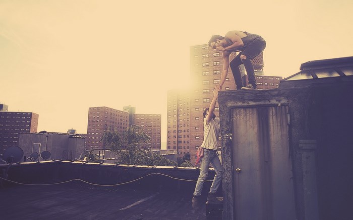 Two men helping each other on a rooftop