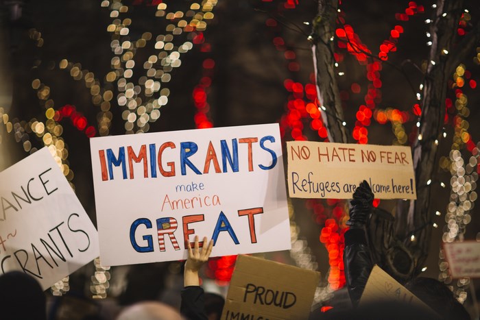 Protestors hold signs supporting immigrants and refugees