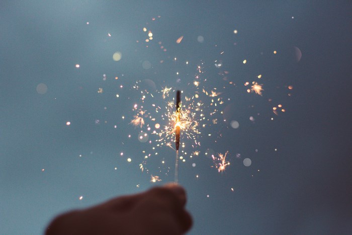 Sparkler with sparks against a blue sky