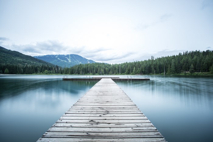Wooden dock on a calm lake with mountains and forest