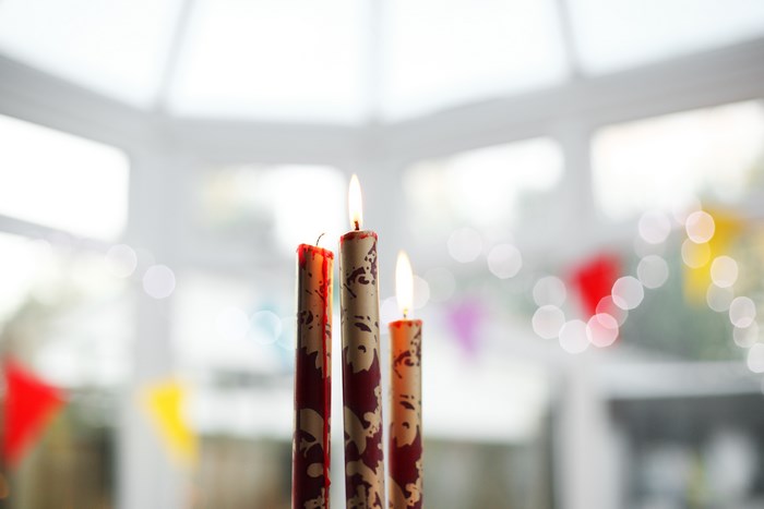 Three lit candles with red and white patterns