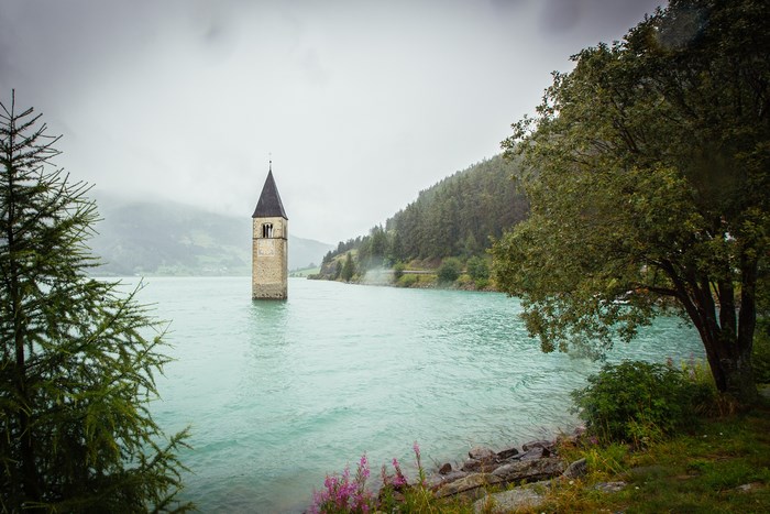 Submerged church tower in a turquoise lake in Italy