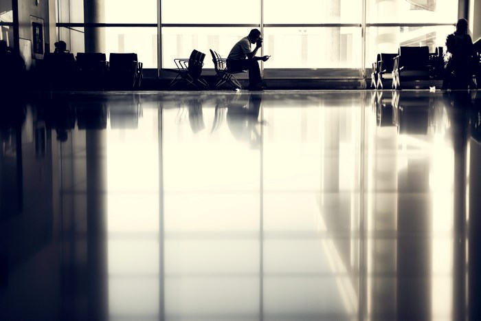 Man sitting in airport waiting area with phone
