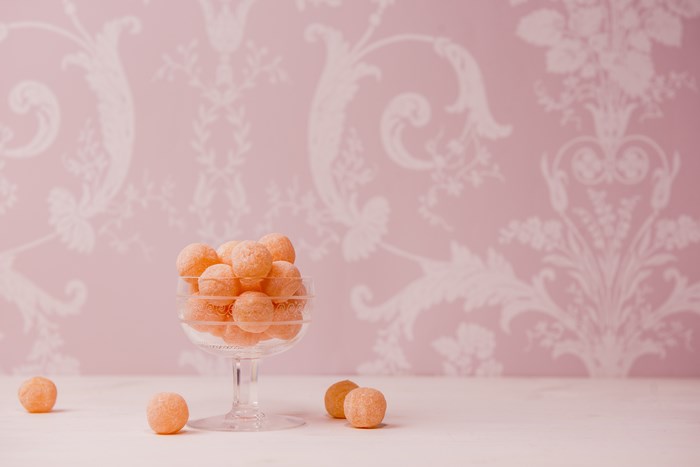 Pink floral wallpaper with bon bons in a glass bowl