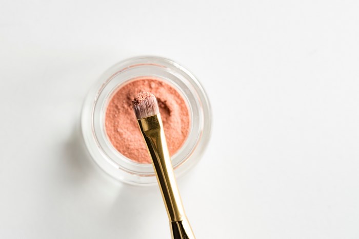 Pink makeup powder with a golden brush