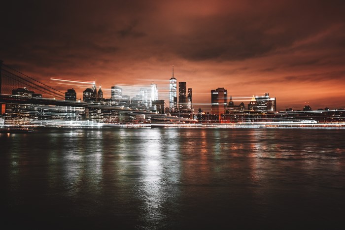 New York City skyline at night with light trails over water
