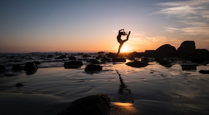 Silhouette of a dancer on a rocky beach at sunset