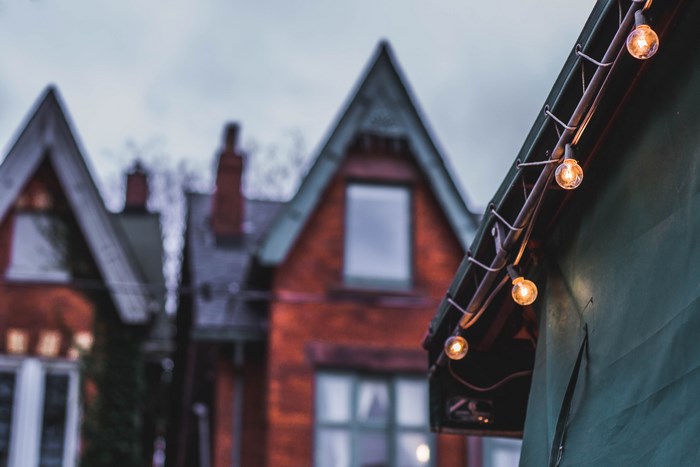 String lights on a roof with houses in the background