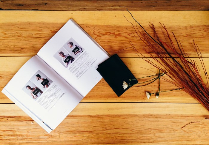 Open book with mugshots and dried flowers on a wooden table