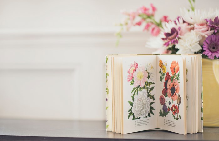 Open book with floral illustrations and a vase of flowers