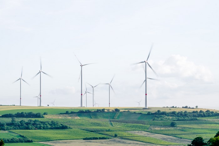 Wind turbines on rolling green hills under a cloudy sky