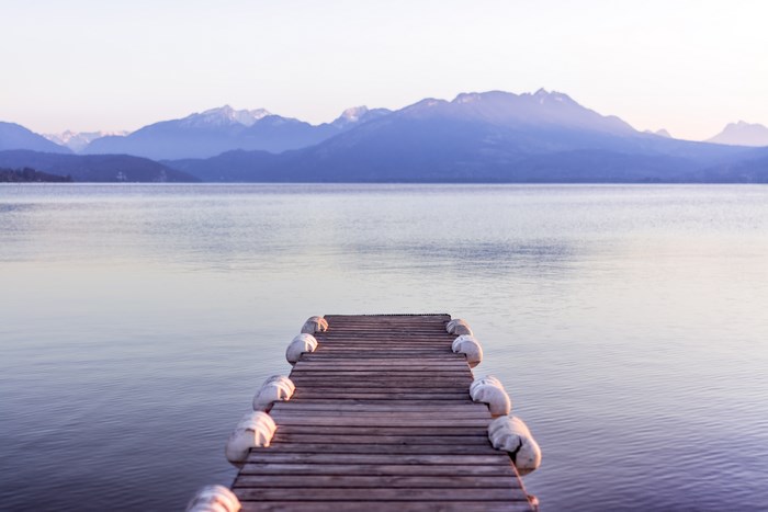Wooden dock on a calm lake with mountains in the background