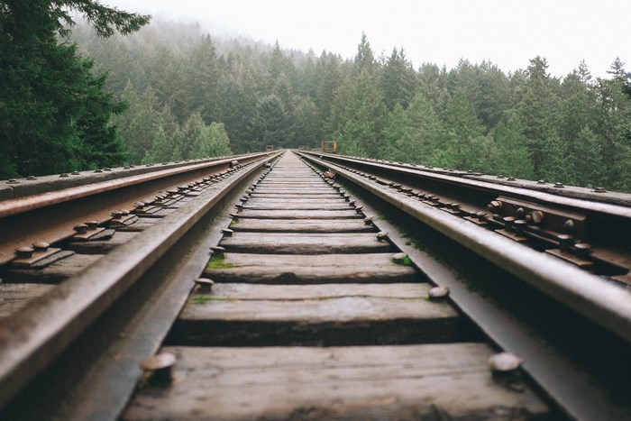 Railroad tracks through a foggy forest