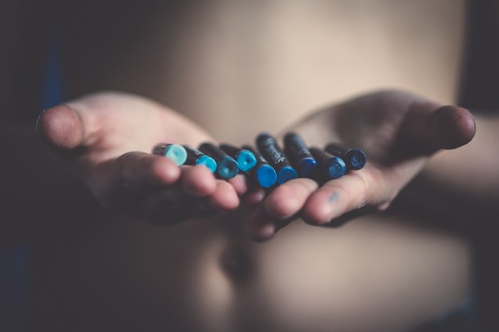 Hands holding blue oil pastels