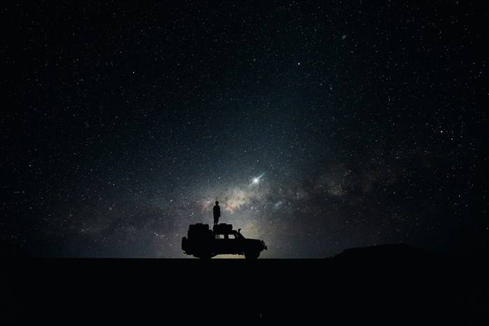 Silhouette of Man Standing on Jeep Under Starry Sky