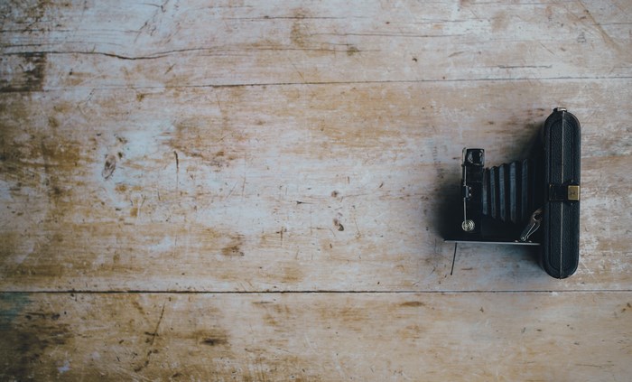 Vintage black bellows camera on a wooden tabletop