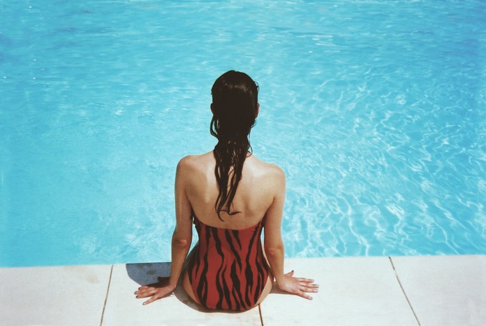 Woman Sitting Poolside in Red Striped Swimsuit