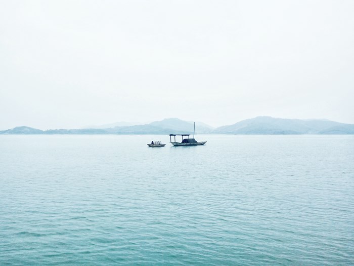 Two boats on a calm lake with distant hills