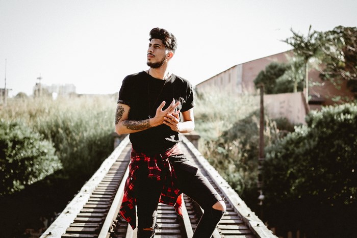 Man with tattoos on railroad tracks